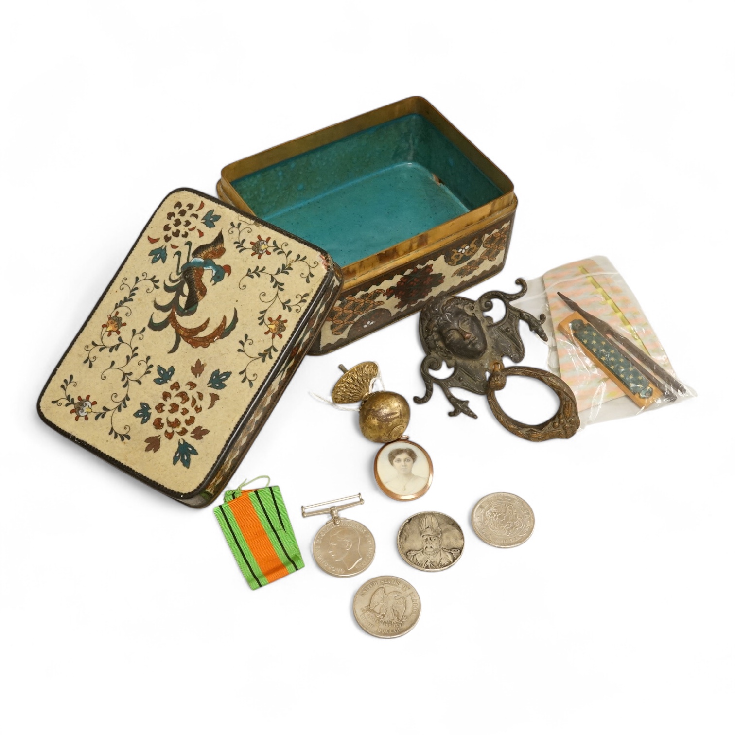 A large cloisonné enamel box containing a cast mask handle, an oval hair pendant, coins and medals, etc.